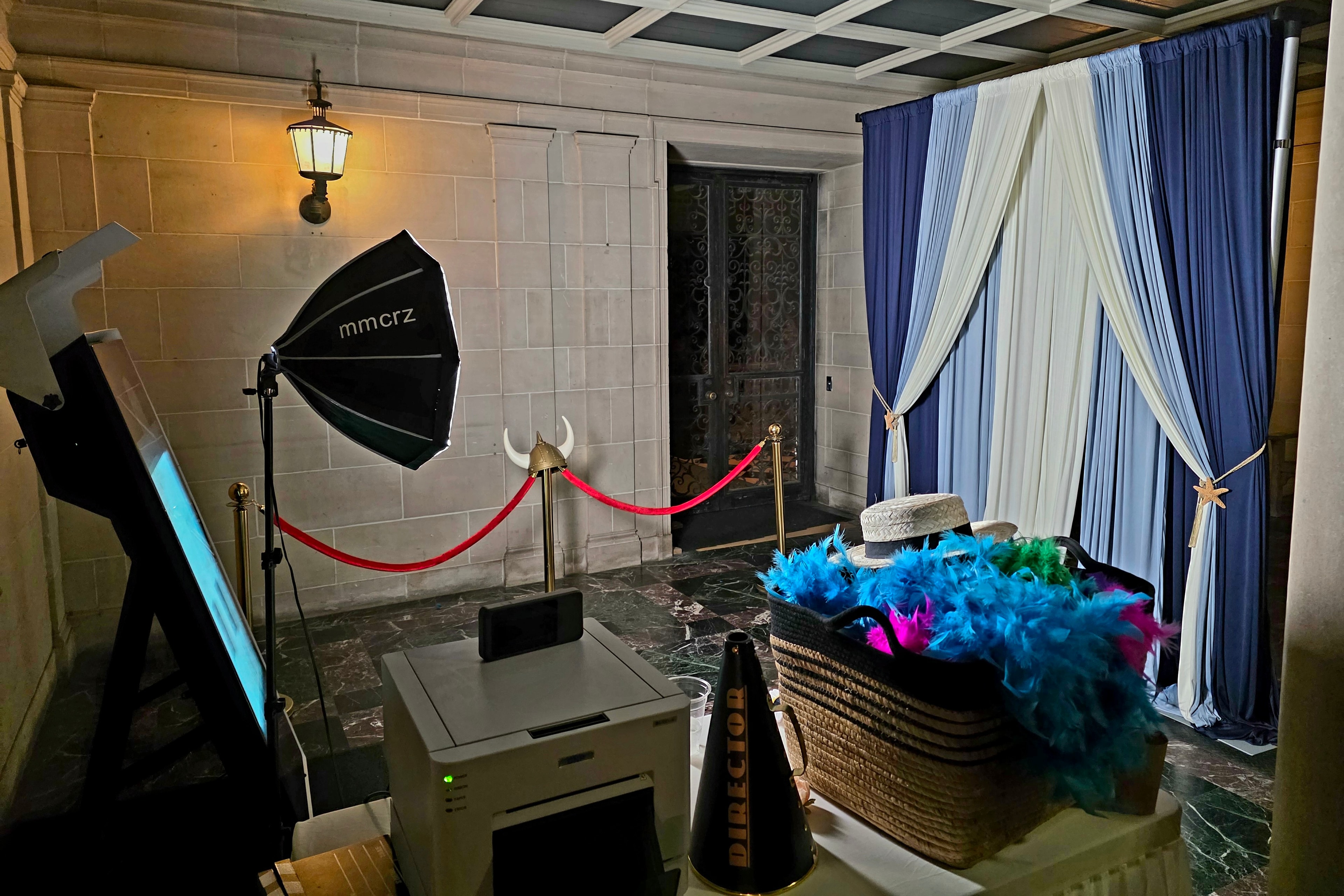 The Filminator Booth setup with professional lighting, printer, props basket, and blue-and-white curtain backdrop at a venue